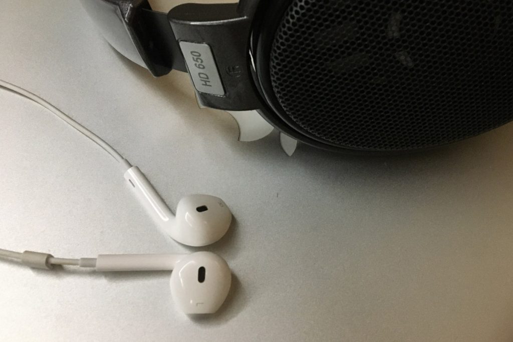 Headphone preto e fone de ouvido Iphone sobre tampa Macbook.