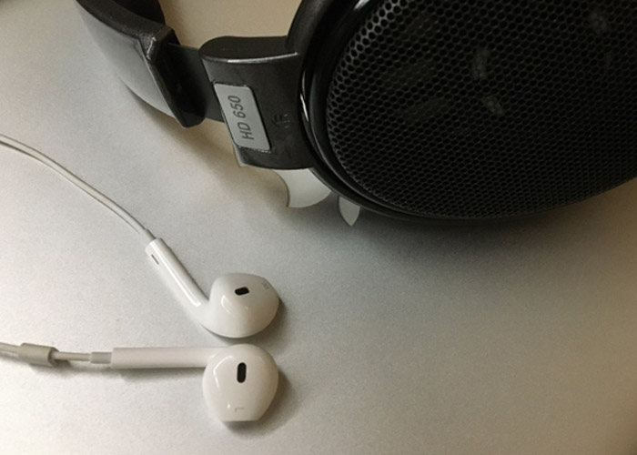 Headphone preto e fone de ouvido Iphone sobre tampa Macbook.